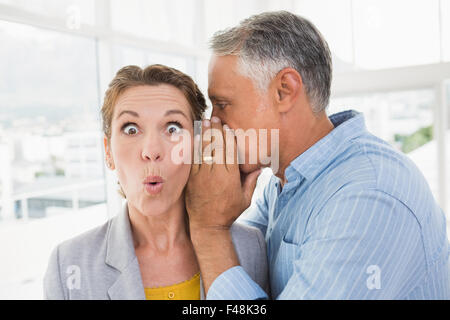 Geschäftsmann telling Geheimnis um eine Geschäftsfrau Stockfoto