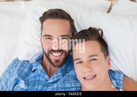 Glückliche homosexuelle Paar am Bett liegen und Blick in die Kamera Stockfoto