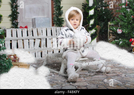 Kind sitzt auf Schlitten mit Schnee in Händen Stockfoto