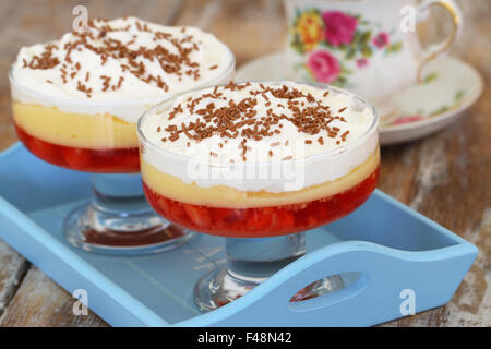 Traditionellen Erdbeer Trifle Dessert mit frischer Sahne und bestreut mit Schokolade auf Tablett aus Holz Stockfoto