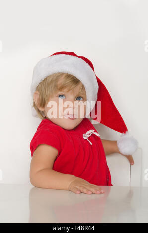 Kind verkleidet am Tisch als Weihnachtsmann. Stockfoto