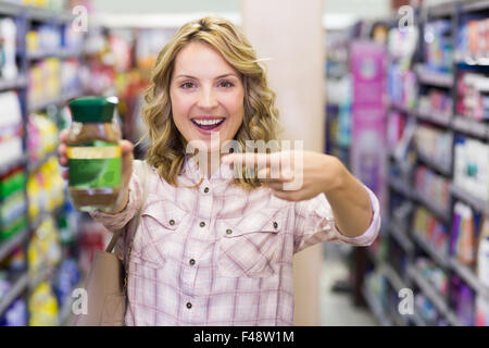 Glücklich lächelnd blonde Frau, die ein Produkt Stockfoto