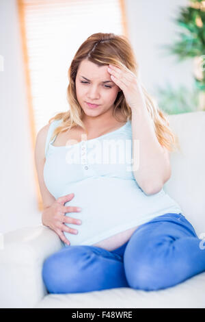 Schwangere Frau, die Kopfschmerzen auf couch Stockfoto