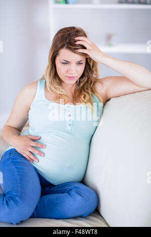 Schwangere Frau, die Kopfschmerzen auf couch Stockfoto