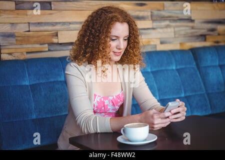 Glücklich lächelnde Frau mit dem Kaffee und Uisng ihr smartphone Stockfoto