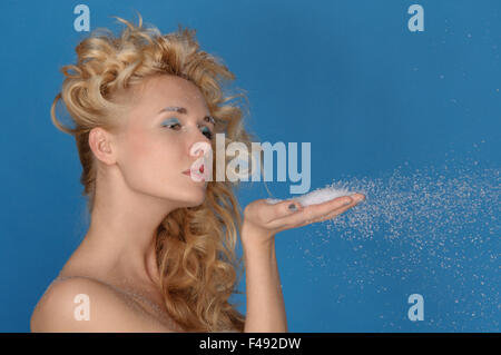 schöne Frau bläst Schnee mit Händen Stockfoto