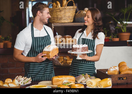 Lächelnde Mitarbeiter mit Brot und Kuchen Stockfoto