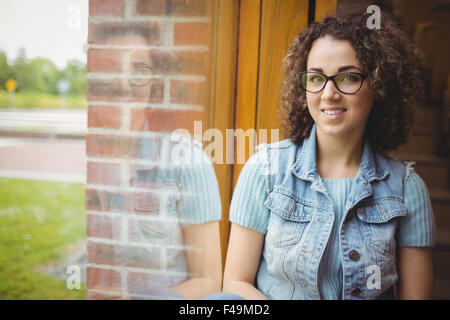 Hübsche Studentin Fenster in die Kamera Lächeln sitzen Stockfoto