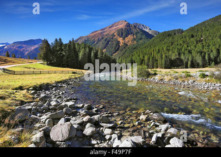 Der Fluss unter grünen Bergwiesen Stockfoto