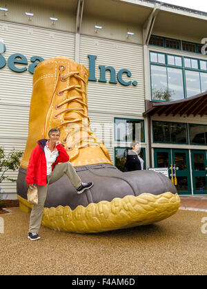 Frau, stützte sich auf die riesige l.l. Bean ikonischen Boot vor ihrem Geschäft in Freeport, Maine Stockfoto