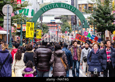 Ikuta Shinto Schrein, Japan während Shogatsu, neues Jahr. Menschenmassen entlang der Avenue zum Heiligtum mit Ständen auf beiden Seiten und über Kopf anzeigen. Stockfoto