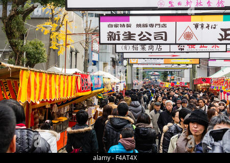 Ikuta Shinto Schrein, Japan während Shogatsu, neues Jahr. Menschenmassen entlang der Avenue zum Heiligtum mit Ständen auf beiden Seiten und über Kopf anzeigen. Stockfoto