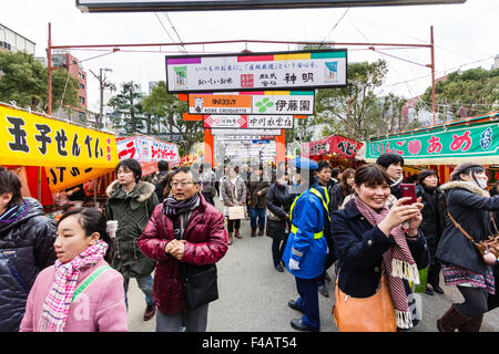 Ikuta Shinto Schrein, Japan während Shogatsu, neues Jahr. Menschenmassen entlang der Avenue zum Heiligtum mit Ständen auf beiden Seiten und über Kopf anzeigen. Stockfoto