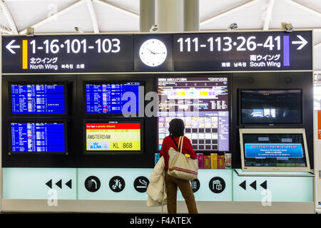 Flughafen Kansai in Osaka, Japan. Flug Informationen in der internationalen Abflughalle mit Frau, Beifahrer, Kontrolle der Flugzeit und Tor. Stockfoto