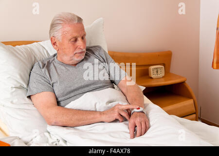 Senior-Rufhilfe mit Notfall-Telefon im Bett Stockfoto
