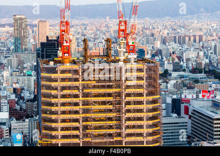 Japan, Osaka, Ansicht von Umeda Sky Building, Bürogebäude mit vier Kränen auf jeder oberen Ecke gebaut wird. Stadt Hintergrund. Goldene Stunde. Stockfoto