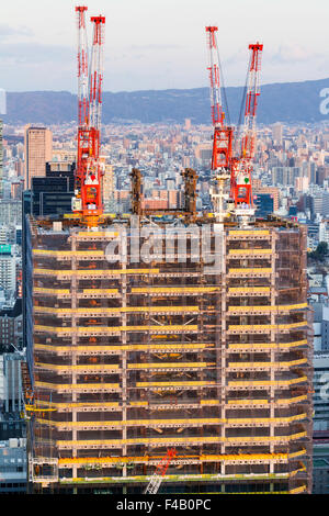 Japan, Osaka, Ansicht von Umeda Sky Building, Bürogebäude mit vier Kränen auf jeder oberen Ecke gebaut wird. Stadt Hintergrund. Goldene Stunde. Stockfoto