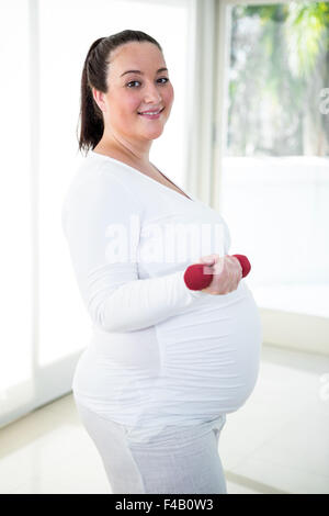 Schwanger lächelnde Frau heben Hantel Stockfoto