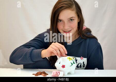 Jugendliche, die Fütterung Sparschwein Stockfoto