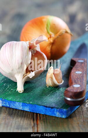 Knoblauch und Zwiebeln auf ein Schneidebrett. Stockfoto