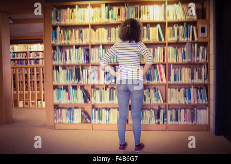 Hübsche Studentin in Bibliothek Buch auswählen Stockfoto