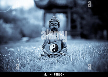 Yin & Yang Zeichen mit Buddha-Statue Stockfoto