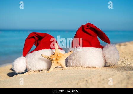 Romantisches Silvester am Meer. Weihnachtsferien. Santa Hüte am Sandstrand Stockfoto