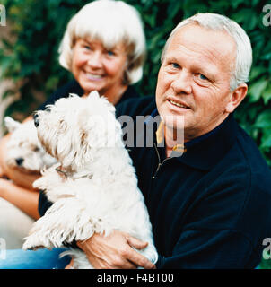 Älterer Mann mit einem Hund in ihrem Schoß und ältere Frau saß neben dem Hund in seinem Schoß. Stockfoto