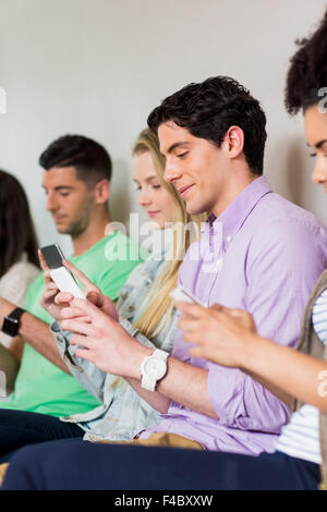 Studenten, die mit ihren Smartphones in Folge Stockfoto