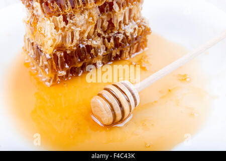 Waben mit Honig und Honig-Stick auf weißem Hintergrund Stockfoto