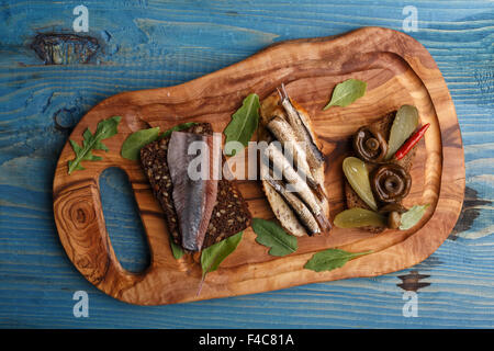 Verschiedene belegte Brötchen aus Vollkorn und Schwarzbrot mit verschiedenen Belägen über blauen hölzernen Hintergrund. Stockfoto