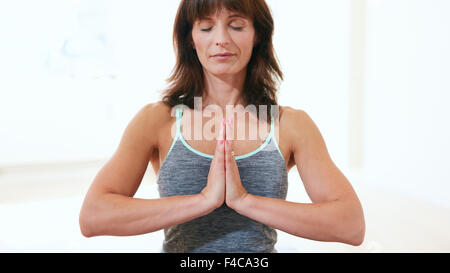 Porträt von gesunden Frau Meditation Yoga zu praktizieren. Reife kaukasischen Frauen sitzen in der Turnhalle mit den Händen trat meditiert Stockfoto