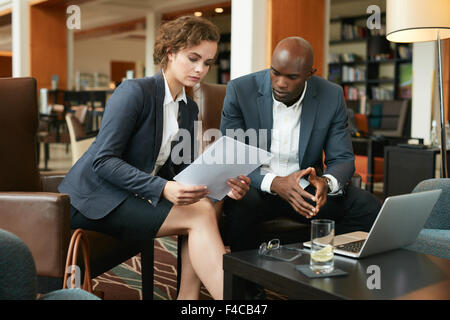Aufnahme von zwei junge Geschäftsleute sitzen zusammen in einem Café Vertrag Zeitungen zu lesen. Führungskräfte treffen sich in einer Hotel-Lobby. Stockfoto