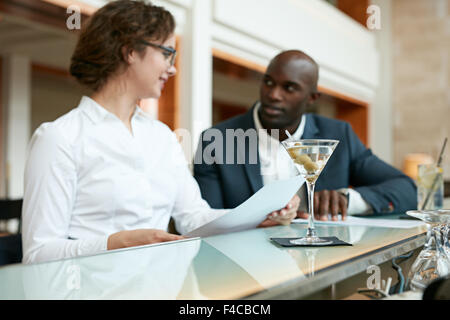 Cocktail am Zähler mit zwei Geschäftsleute sitzen im Hintergrund arbeiten im Café diskutieren. Stockfoto