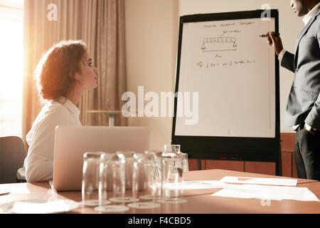 Porträt eines Mannes, der einige seiner Gedanken auf einem Flip Board teilen. Unternehmer, die etwas an einen Kollegen bei einem Whiteboard zu erklären Stockfoto