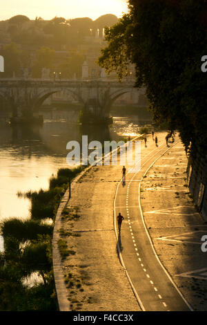 Wanderweg entlang der Seite des Flusses Tiber bei Wanderern und Joggern einfahren am späten Nachmittag und die Sant'Angelo Brücke, Rom, Italien Stockfoto