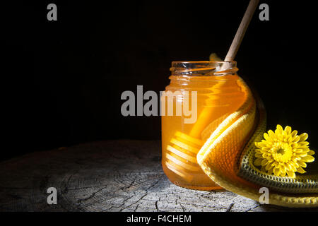 Glas Honig und halten Sie sich Honig auf einem hölzernen Hintergrund Stockfoto