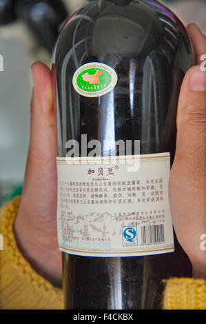 China, Ningxia, Yinchuan. Arbeiter der hand Kleber Etiketten auf Flaschen Helan Qing Xue Kellerei. Stockfoto