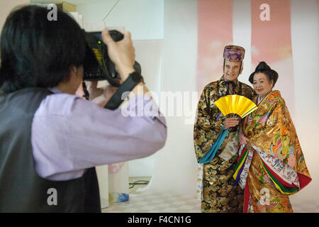 California paar geschmückt, als letzter König und die Königin von Ryūkyū (1872) auf ihr 55. Hochzeitstag-Foto auf dem Bridal Palace Salon in Naha, Okinawa, Japan vorzubereiten. (MR) Stockfoto