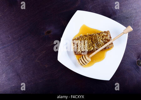weißen Teller mit Waben auf einem dunkelblauen Hintergrund aus Holz Stockfoto