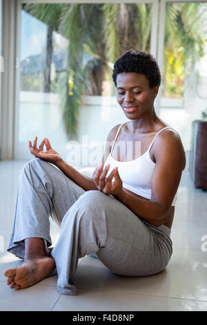 Fröhliche schwangere Frau sitzen in Lotus-pose Stockfoto