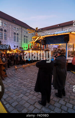 Das alpine Weihnachtsdorf im Kaiserhof der Residenz, das Schloss der Bayerischen Könige. Konzert mit Alphorn (Alphorn). München, Bayern, Deutschland. Stockfoto