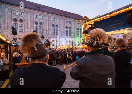 Das alpine Weihnachtsdorf im Kaiserhof der Residenz, das Schloss der Bayerischen Könige. Konzert mit Alphorn (Alphorn). München, Bayern, Deutschland. Stockfoto