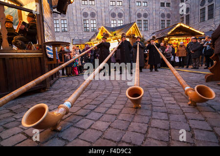 Das alpine Weihnachtsdorf im Kaiserhof der Residenz, das Schloss der Bayerischen Könige. Konzert mit Alphorn (Alphorn). München, Bayern, Deutschland. Stockfoto