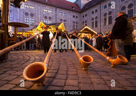 Das alpine Weihnachtsdorf im Kaiserhof der Residenz, das Schloss der Bayerischen Könige. Konzert mit Alphorn (Alphorn). München, Bayern, Deutschland. Stockfoto