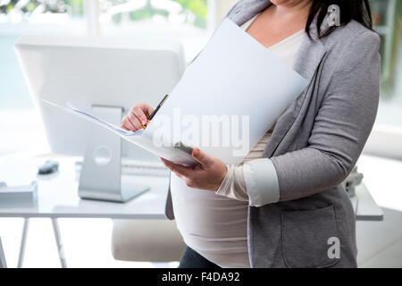 Schwanger Geschäftsfrau beobachten Sie ihre Ordner Stockfoto