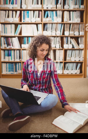 Hübsche Studentin in der Bibliothek mit laptop Stockfoto