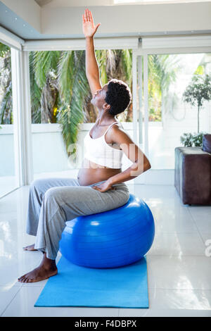 Schwangere Frau Dehnung sitzend auf Gymnastikball Stockfoto