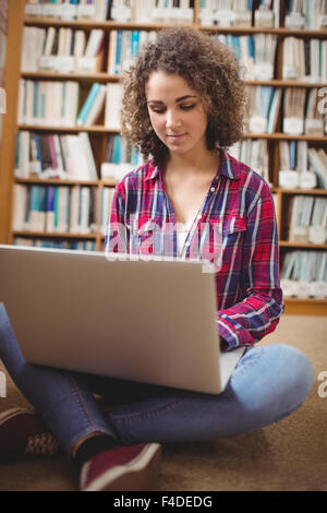 Hübsche Studentin in der Bibliothek mit laptop Stockfoto