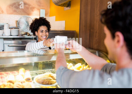 Kellnerin serviert Cappuccino an Kunden Stockfoto